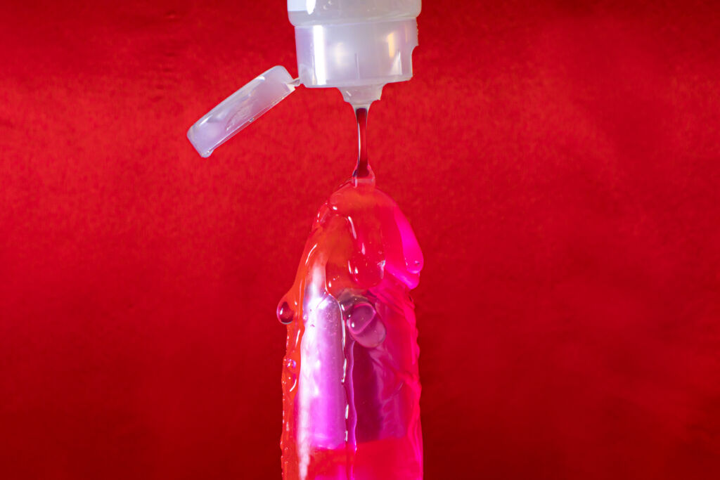 Lubricant for sex drips on a vibrator on a red background.